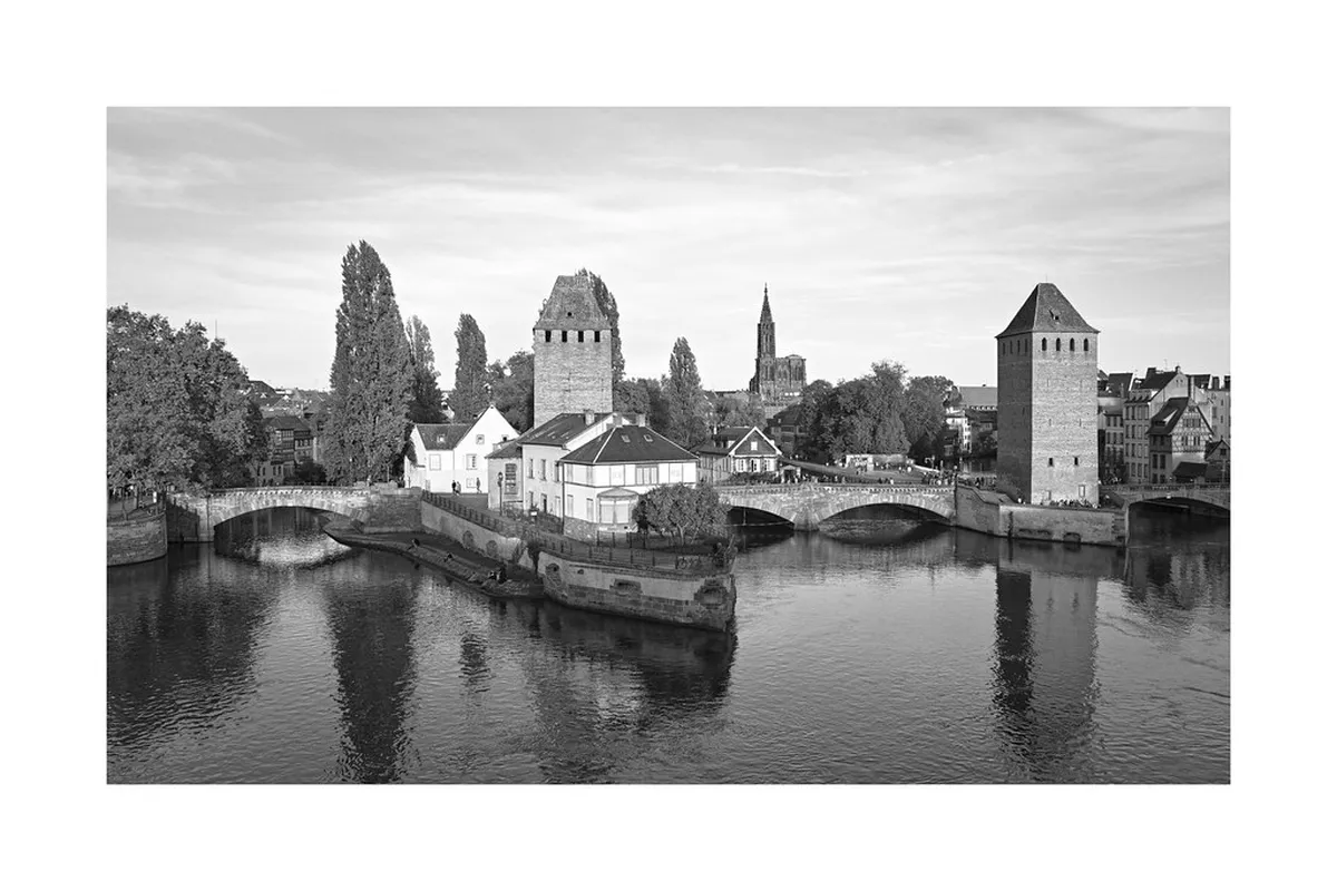 The arcaded Barrage Vauban stretching across the River Ill in Strasbourg, with the towers of the Ponts Couverts beyond