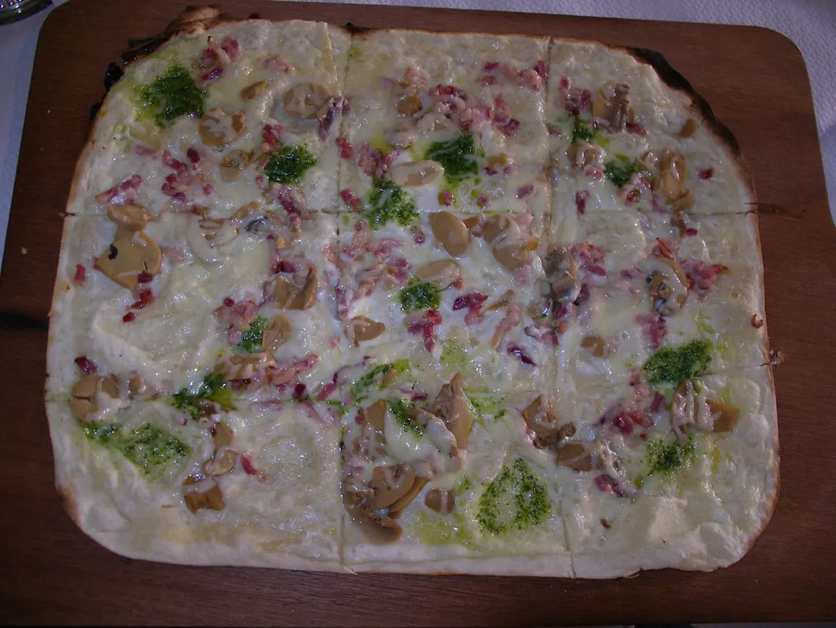 Traditional Alsatian Tarte Flambée (Flammekueche) with crème fraîche and lardons
