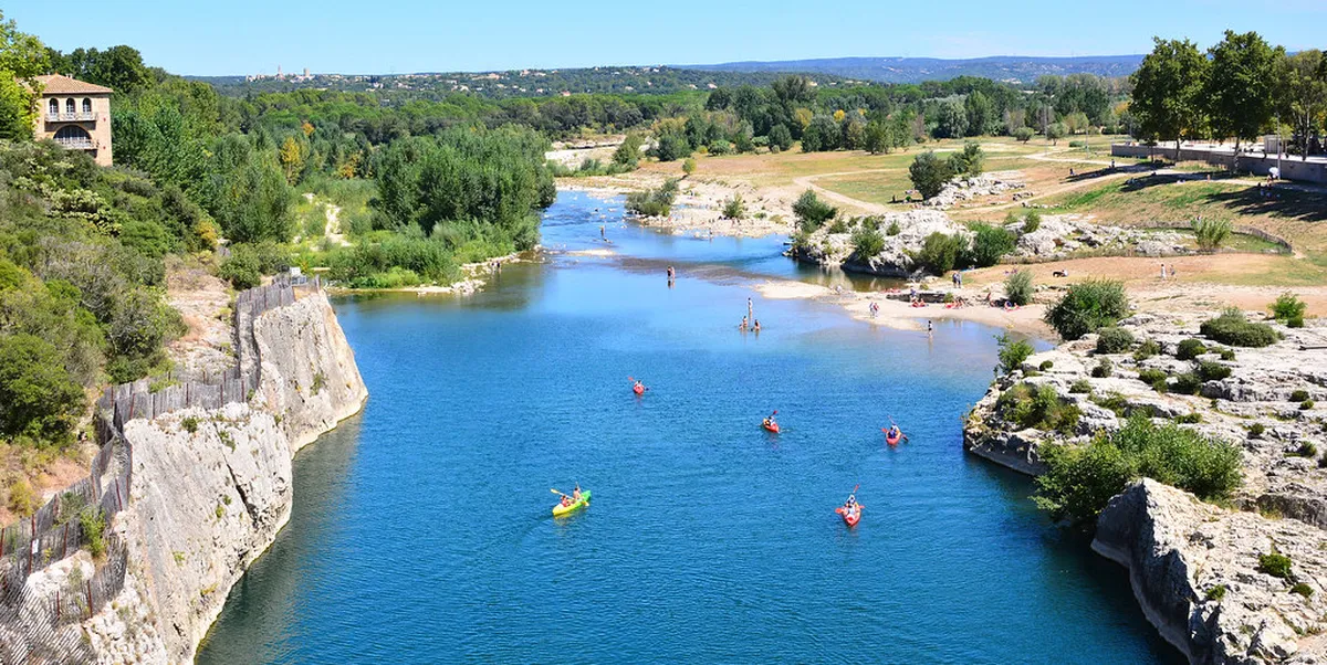 Swimmers enjoying the cool Gardon River beneath Pont du Gard arches