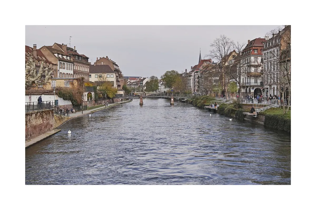 Strasbourg Ill river with outdoor café terrace and boats in summer sunshine